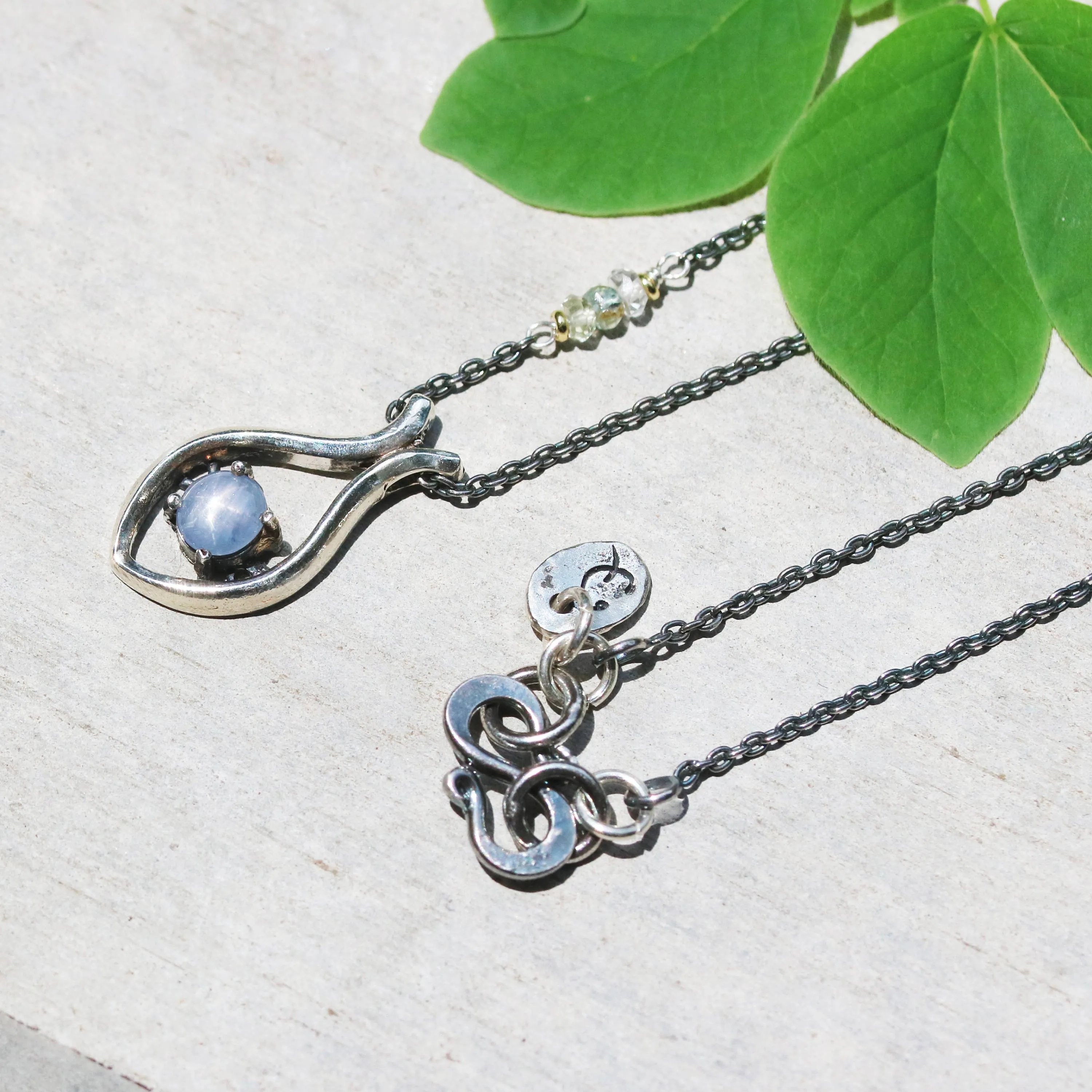 Silver fish shape necklace and cabochon star blue sapphire at the center with aquamarine beads secondary on oxidized sterling silver chain