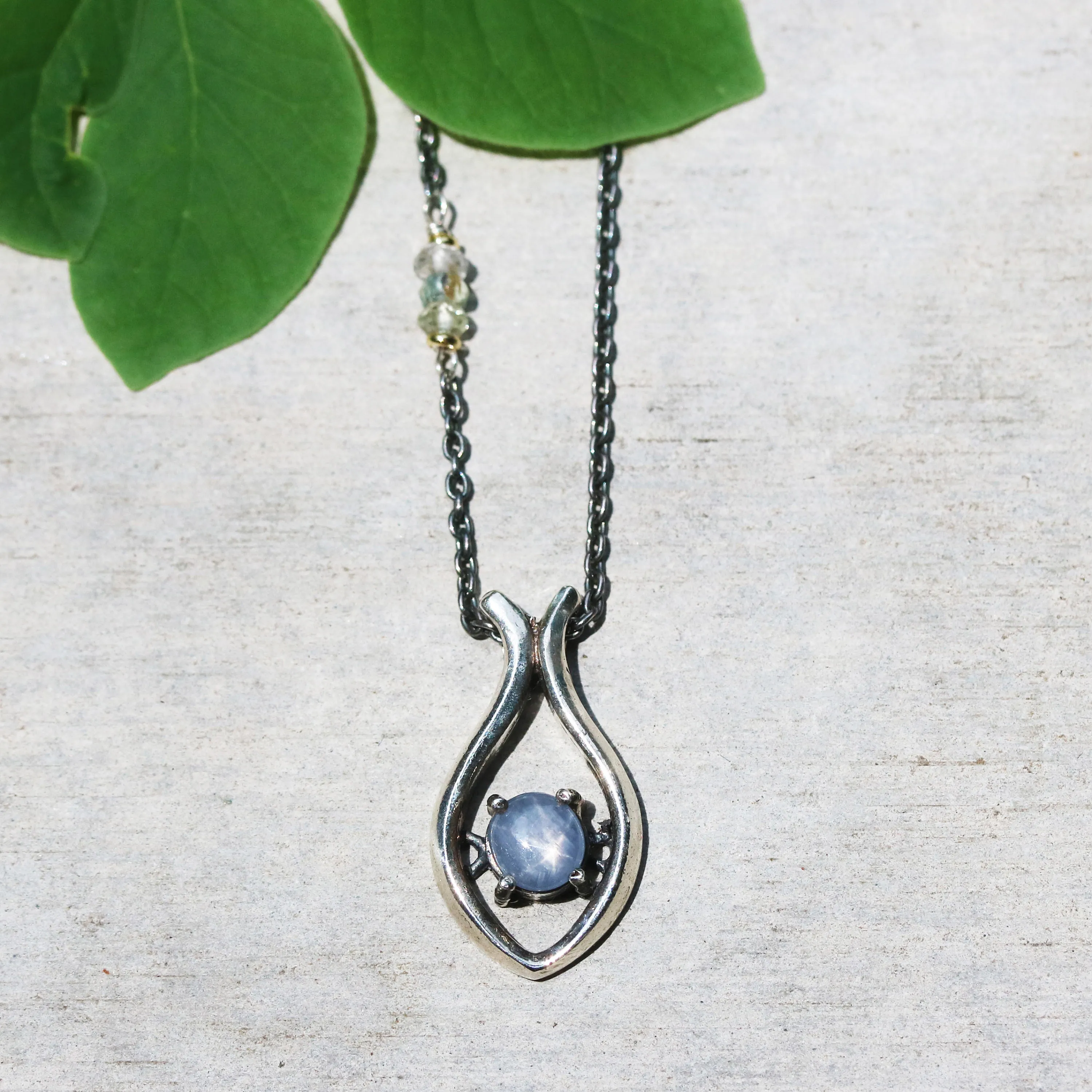 Silver fish shape necklace and cabochon star blue sapphire at the center with aquamarine beads secondary on oxidized sterling silver chain